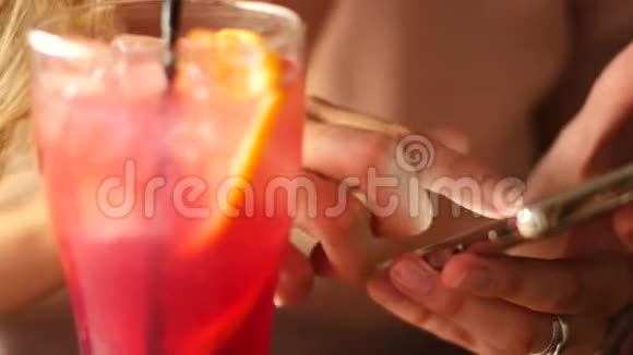 一位手里拿着智能手机的美女在酒吧喝一杯鸡尾酒视频的预览图