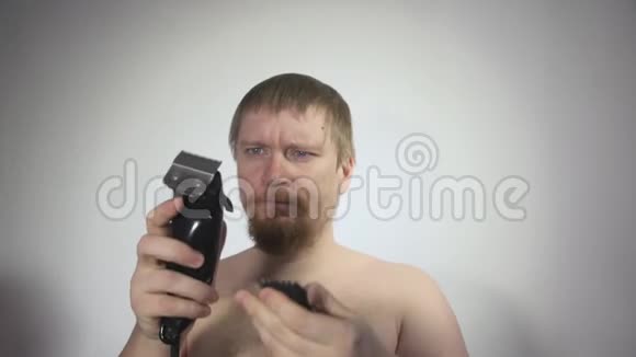 男人用剪刀在白色背景上剃光头拍摄特写镜头视频的预览图