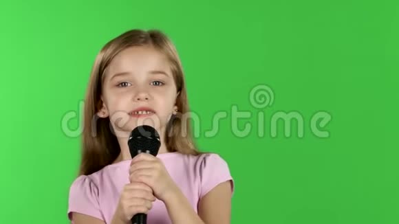 童女将歌曲唱入话筒绿色屏幕视频的预览图