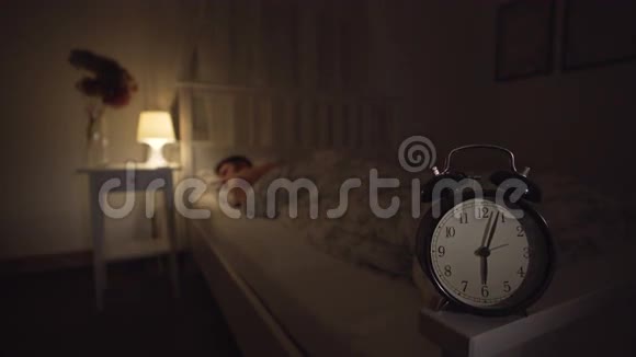 年轻人睡在床上前景上有一个钟显示早上6点视频的预览图