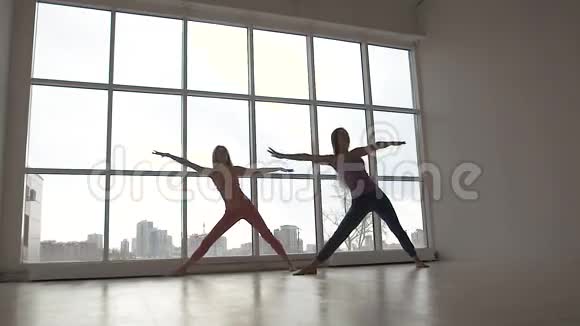 漂亮的年轻女性一起练习三角瑜伽姿势视频的预览图