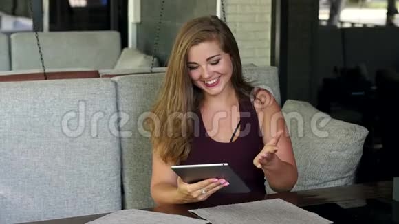 一个体重超标的漂亮女孩坐在一家有平板电脑的餐馆里视频的预览图