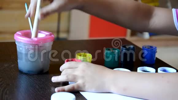小可爱的男孩在桌上画家牌男孩画油漆和刷子体贴认真等待视频的预览图