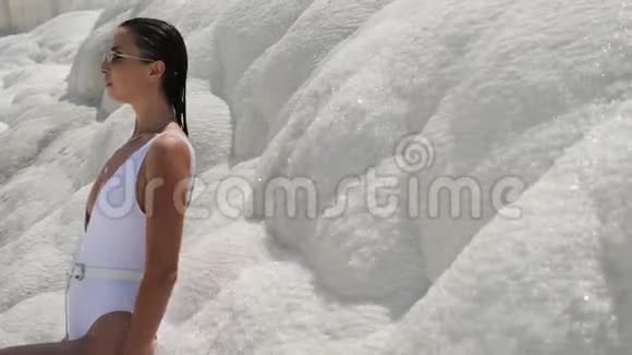 穿着白色泳衣的性感年轻女子站在白色的山上视频的预览图