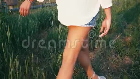 年轻漂亮的女人穿着运动鞋和短裤在草地上散步带着绿草自然的慢动作视频女孩视频的预览图