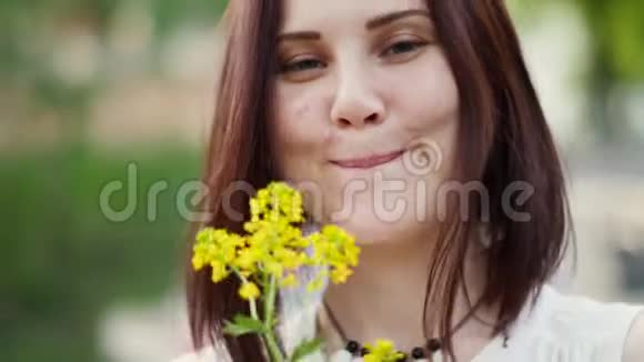 户外一个微笑的女人的肖像女人手中的黄花视频的预览图