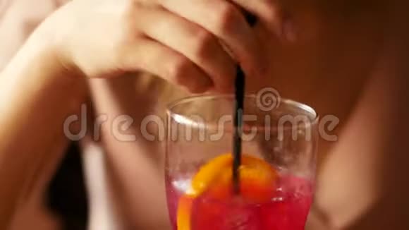 一位手里拿着智能手机的美女在酒吧喝一杯鸡尾酒视频的预览图
