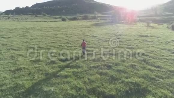 在绿油油的草地上飞过运动员在山上日落平的颜色视频的预览图