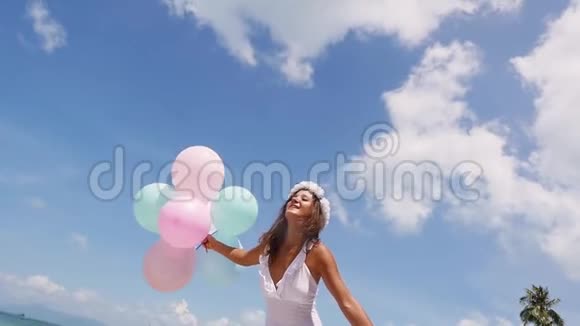 底部的欢乐女孩在海滩上奔跑手拿气球在蓝天背景上慢动作视频的预览图