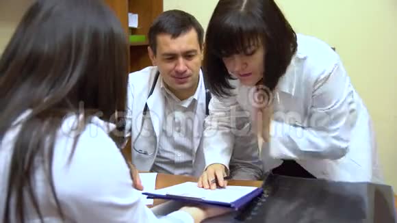 一群医生在说话两个女人和一个男人在文件夹中查看文件视频的预览图