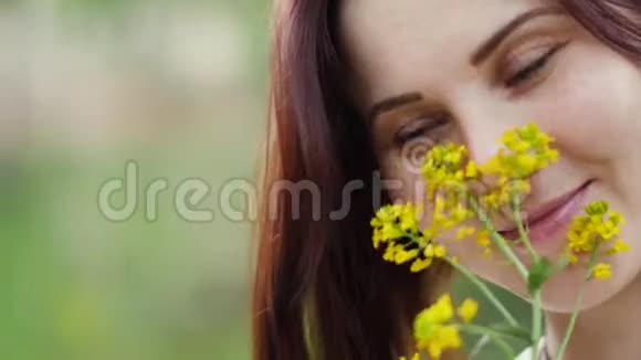 户外一个微笑的女人的肖像女人手中的黄花视频的预览图