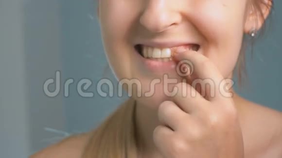 特写镜头显示年轻女子将一块粘在牙齿上的食物眨眼视频的预览图