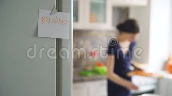 家中厨房里有一位背景女士cookinf上的早餐纸标牌视频的预览图