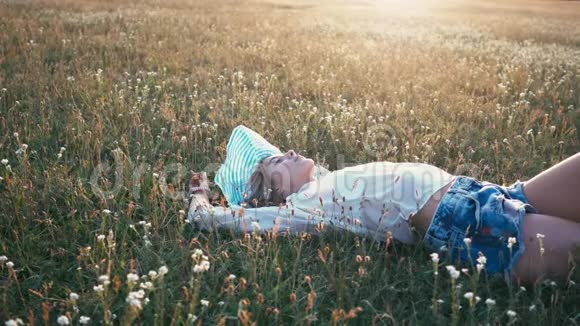 美丽的微笑女孩躺在春田上草甸充满欢笑和快乐的年轻女模特的健康画像视频的预览图