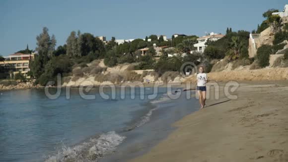 戴着耳机的快乐女孩正在海边奔跑视频的预览图