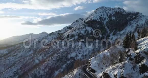 冬季白雪山上沿道路的向后俯视森林树林雪山街道视频的预览图