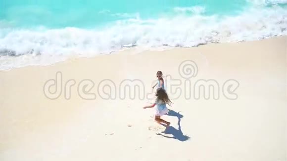 可爱的孩子们在浅水的海滩上一起玩从荒无人烟的海滩上方看绿松石水视频的预览图