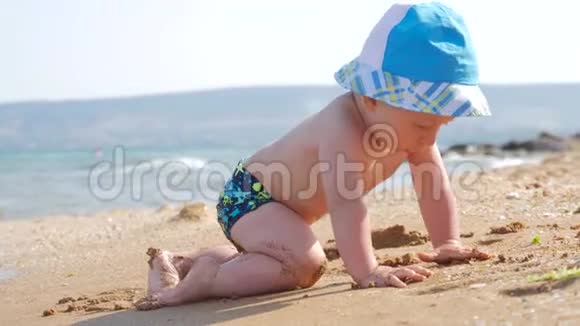 小男孩在海滩上潮湿的沙滩上玩耍他学会爬行波浪拥抱他视频的预览图