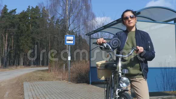 在公共汽车站骑自行车和篮子的女人视频的预览图