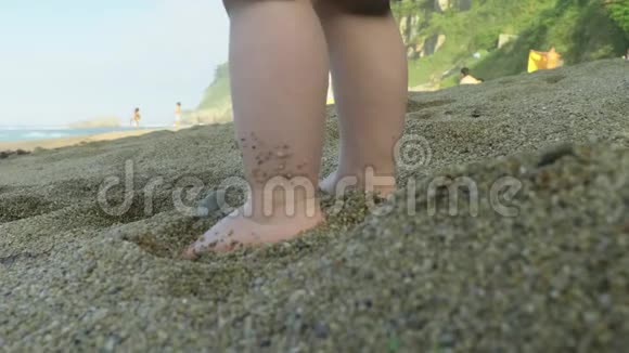 在温暖的阳光下在诺森西班牙海滩温暖的沙滩上小男孩的脚视频的预览图