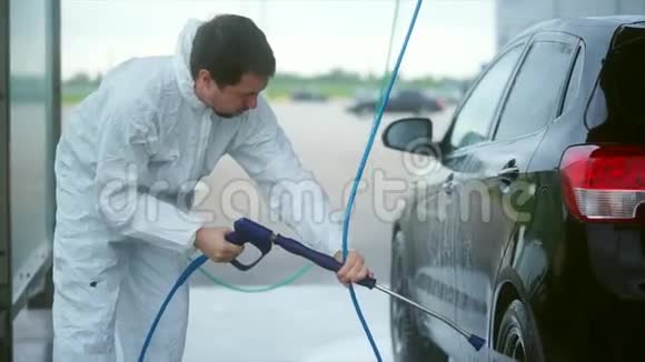 年轻的白种人洗他的车洗车自助服务泡沫洗掉视频的预览图