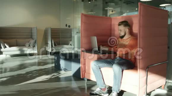 穿橙色套头衫的人在笔记本电脑上工作视频的预览图