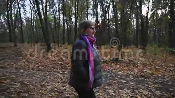 老妇人走在秋天的森林里看着树梢视频的预览图