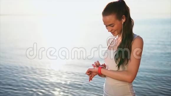 年轻微笑的女人在外面使用智能手表触摸屏可穿戴技术视频的预览图
