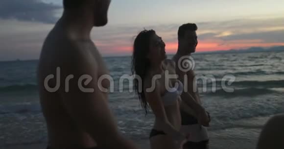 在夕阳下的POV海滩上快乐漫步在夏日海滨假日的人群视频的预览图