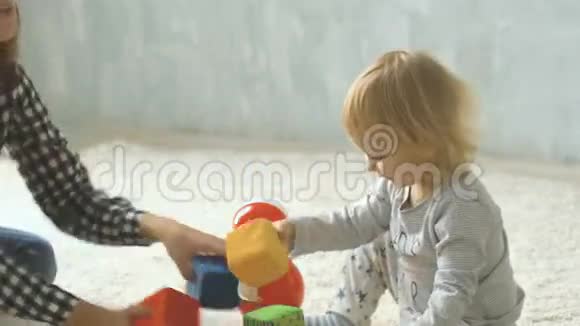 妈妈和她的小女儿在地毯上玩立方体和洋娃娃视频的预览图