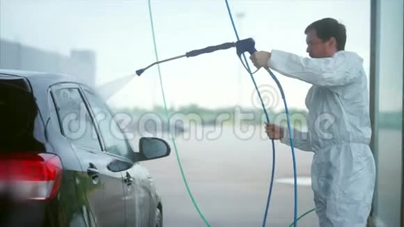 年轻的白种人洗他的车洗车自助服务泡沫洗掉视频的预览图