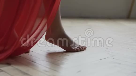 穿着红色长裙的白种人女孩的腿赤脚在房间的地板上行走女人走路通过相机慢镜头视频的预览图