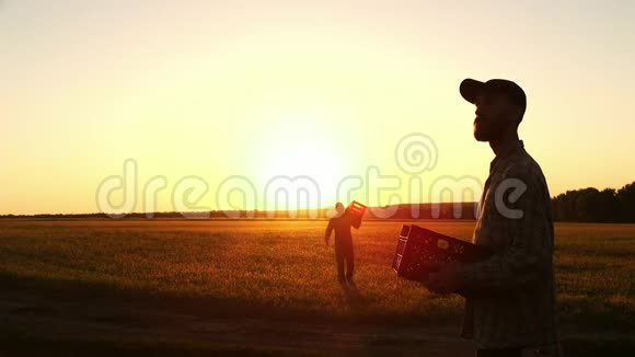 日落时两个农民在一个木箱里一起搬运玉米视频的预览图