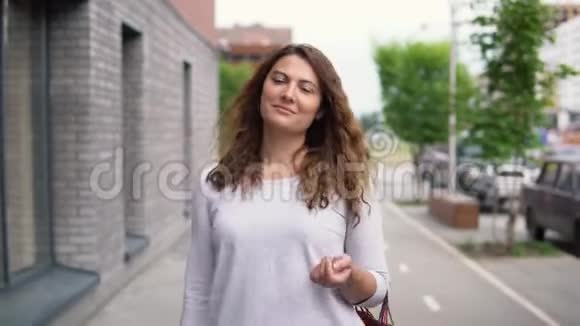 一个漂亮的女孩在购物后走在城市的街道上4K视频的预览图