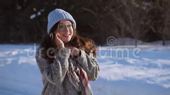 年轻的女人站在冬天的路上她在晴天打电话视频的预览图
