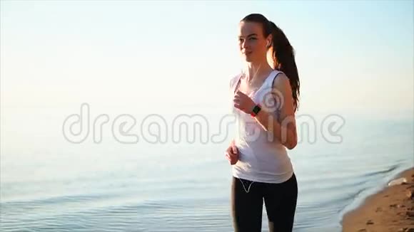 快乐微笑的运动女人在海边的沙滩上慢跑视频的预览图