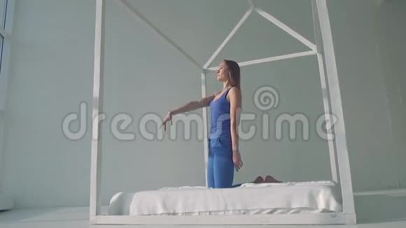 美丽的瑜伽女人在床上练习骆驼姿势视频的预览图