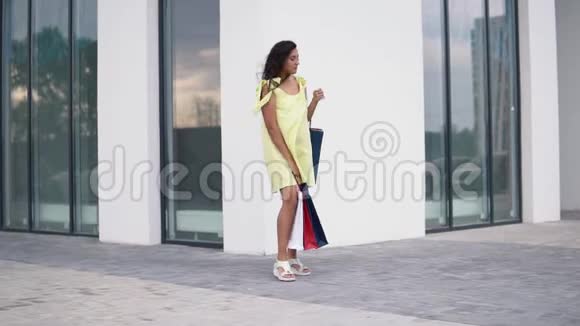 漂亮的女孩模特购物后手里拿着彩色的袋子慢动作视频的预览图