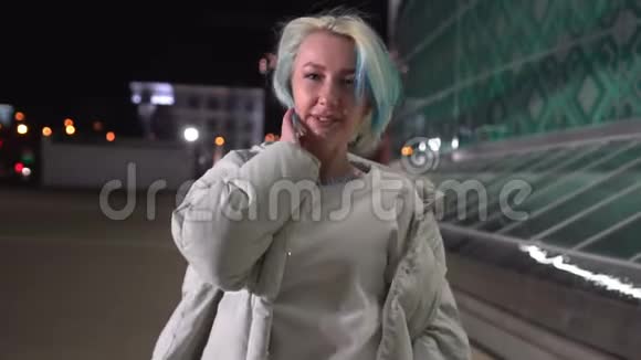 年轻漂亮的女人晚上在城市的广场上走来走去视频的预览图