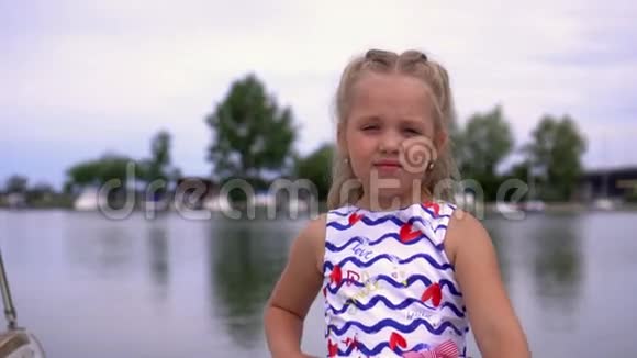那个金发的小女孩在河边的皮尔西为照相机摆姿势那个漂亮的女孩在船上花钱视频的预览图