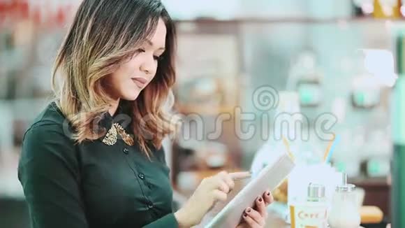 休闲快乐的年轻女人在咖啡馆里用她的平板电脑视频的预览图