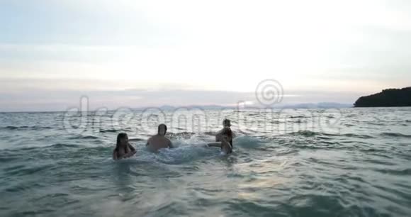 在夕阳下的海上游泳的朋友小组年轻人在沙滩上享受乐趣视频的预览图
