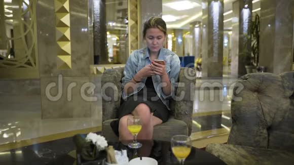 穿着牛仔裤夹克的年轻白种人使用智能手机在社交网络上写信息在表格中的位置视频的预览图