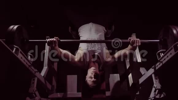 运动青年健身者用沉重的杠铃练习长凳按压视频的预览图