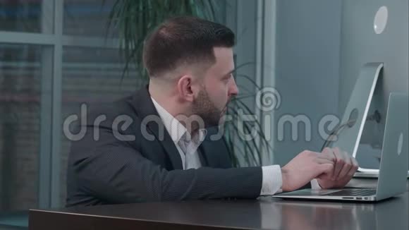 有魅力的高加索商人在工作场所与伴侣交谈时使用笔记本电脑视频的预览图