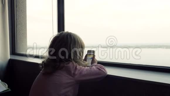 安大略湖和一个在智能手机上看卡通的小女孩视频的预览图