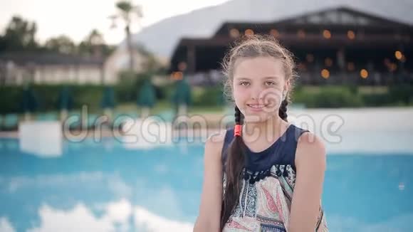年轻女孩坐在游泳池旁边的一座漂亮的房子里视频的预览图