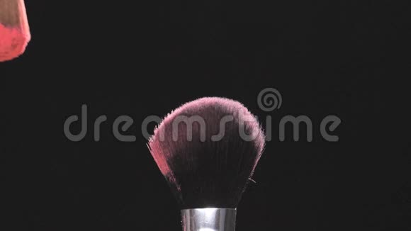 两个黑色背景上有粉红色粉末的化妆刷视频的预览图