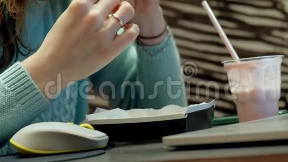女人享受快餐和在咖啡厅工作笔记本电脑视频的预览图