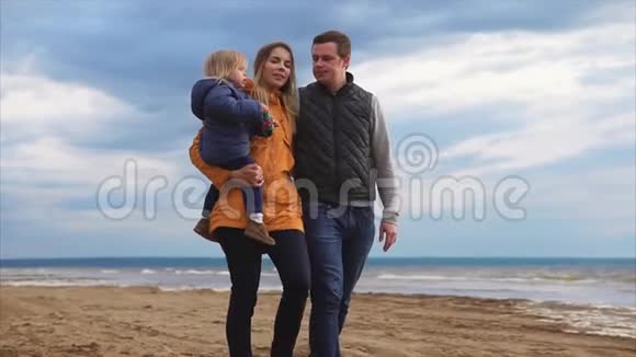 寒冷的一天父母带着小女儿在海边散步视频的预览图